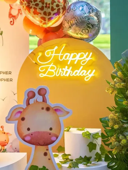 A close-up of our jungle decor, featuring a friendly giraffe, a neon 'Happy Birthday' sign, and lush greenery to complete the look.