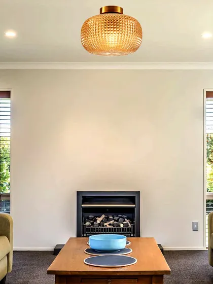This flush-mount ceiling light with a textured amber glass shade brings a warm, inviting glow to a living room. It shows how luxury can take shape even in more compact fixtures.