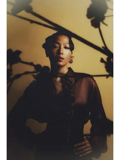 A moody portrait of Patricia with shadows of a branch cast across the background. This technique adds texture and a narrative element to a simple studio portrait.