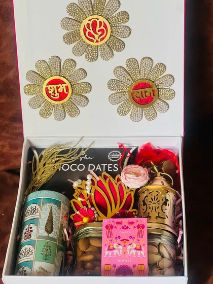 Celebrating the festival of lights with a touch of elegance. This corporate Diwali hamper features traditional items like a brass lantern and dry fruits, alongside modern touches, all presented in a beautifully decorated box.