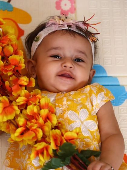 A happy baby in our yellow floral jhabla, holding a bouquet of flowers. These are the moments I cherish and design for.