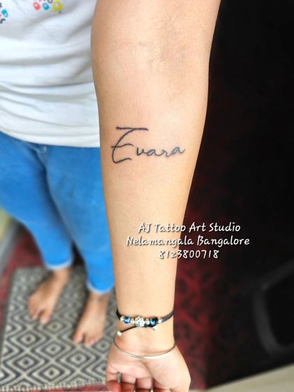 A simple and clean "Evara" name tattoo in a handwritten script style on the forearm.