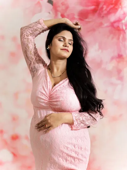 A beautiful, dreamy pose in our studio. The expecting mother in a pink gown with her eyes closed, feeling the moment. The floral backdrop adds to the soft, feminine feel.