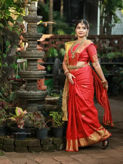 A full-length portrait in a beautiful garden setting. The bride's pose is elegant, and the traditional lamp post adds a classic touch to the scene.