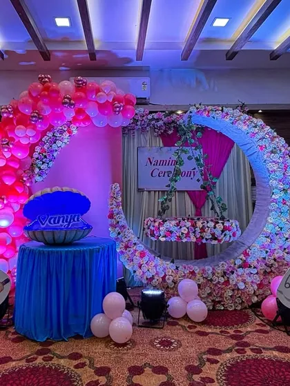 I love creating personalized themes, like this naming ceremony for baby Vanya. The setup includes a beautiful floral moon with a hanging cradle, cute "It's a Girl" cartoon cutouts, and a special seashell prop that opens to reveal the baby's name.
