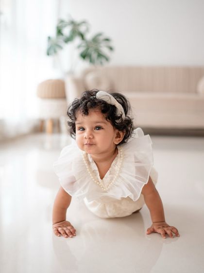 A beautiful baby girl crawling in a lovely white outfit. A perfect shot for a sitter session.