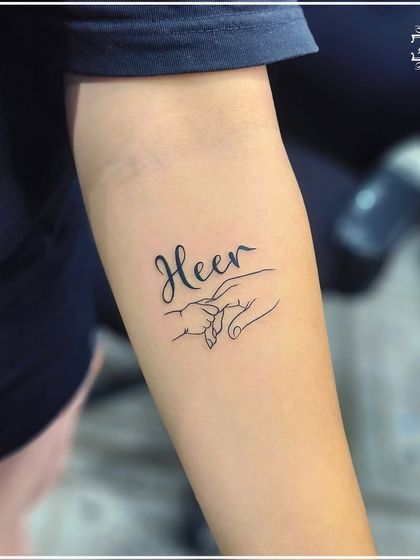Another view of the "Heer" tattoo, showcasing the delicate line work and the personal touch of the combined name and drawing.