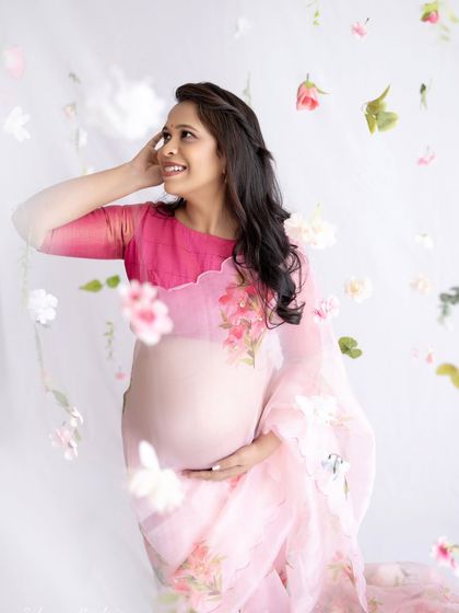 This portrait beautifully showcases the sheer fabric of the floral organza saree over the baby bump, creating a delicate and ethereal effect.