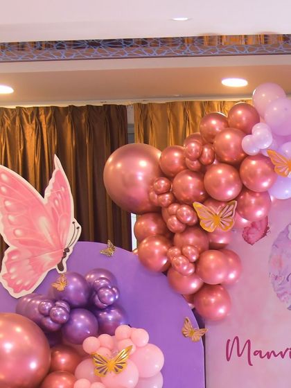 A beautiful balloon arrangement in shades of pink and purple for Manvi's butterfly-themed party. The chrome and pastel balloons are accented with small butterfly cutouts.