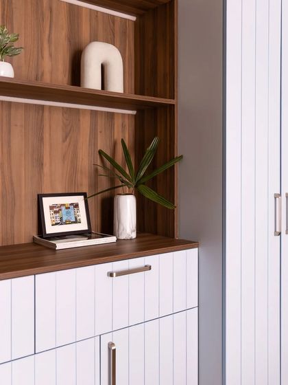 A close-up of the bookshelf, showing the warm wood-textured back panel and the clean white shelves.
