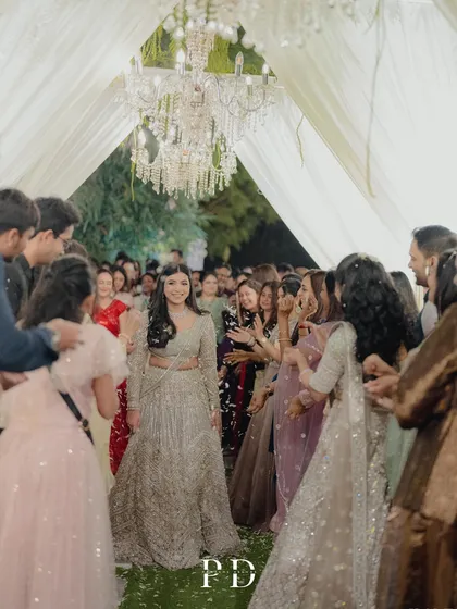 The bride making her entrance through a tunnel of friends and family, with a beautiful chandelier overhead. We design spaces that encourage these kinds of joyful, interactive moments.