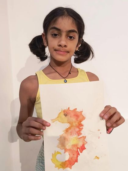 A student shows her beautiful watercolor seahorse, using wet-on-wet techniques to create a lovely blend of orange and yellow.