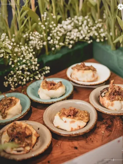 Miniature naan breads topped with a savoury mixture, presented on a wooden board. This is a modern take on a classic Indian combination, perfect for passing around at a Sangeet or reception.
