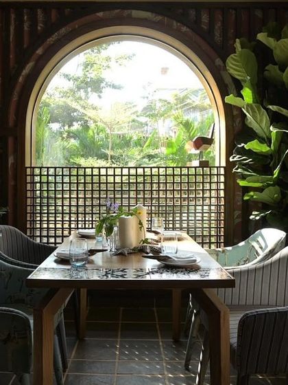 An interior dining table at Sanctuary Bar, set against an arched window that frames a perfect view of the lush Goan landscape outside.