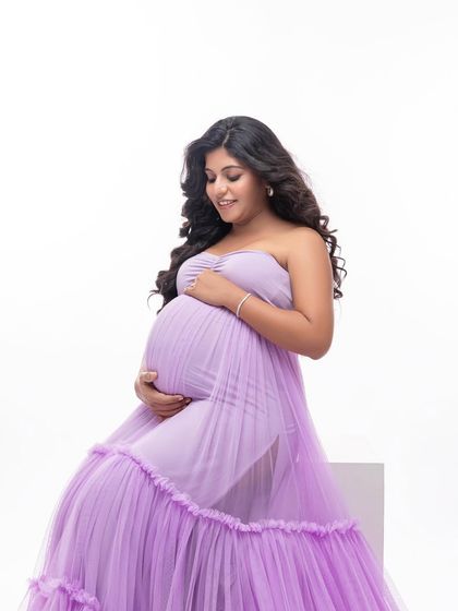 A close-up that captures the delicate texture of the lavender gown and the mother's gentle expression as she looks down at her bump.