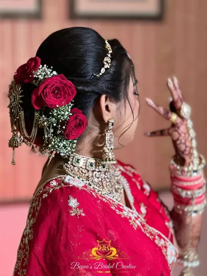 A view of the elegant bridal bun, adorned with fresh red roses and a traditional hair accessory.