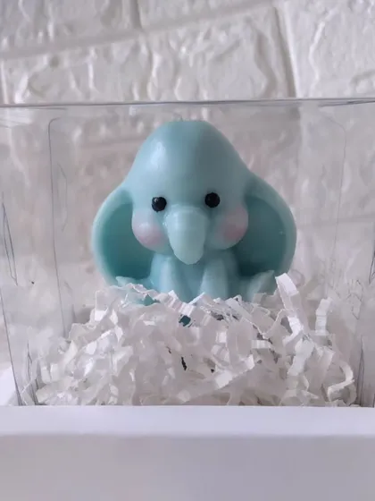 The blue baby elephant candle shown in its clear display box, ready for gifting.