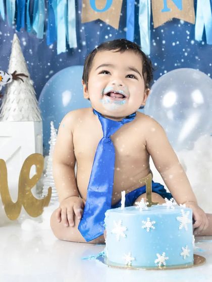 This little guy is all dressed up with a blue tie for his first birthday cake smash. The winter theme adds a magical touch.
