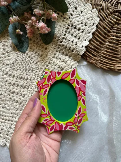 A bright and funky photo frame magnet with pink leaves on a lime green background.