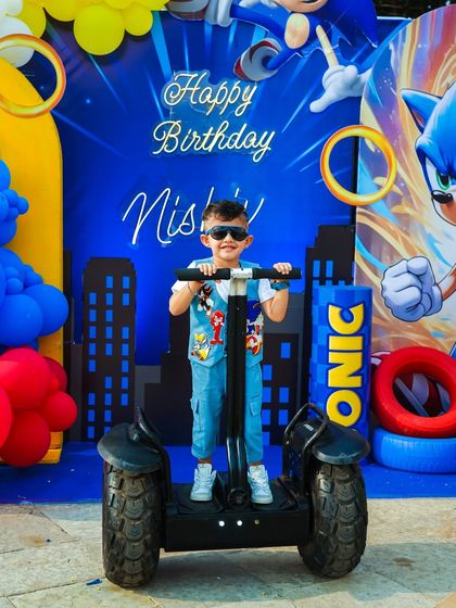The birthday boy looking super cool on a Segway in front of his Sonic-themed birthday backdrop.