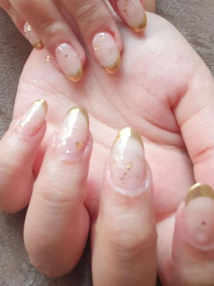 A close-up of the gold chrome French tip design, highlighting the metallic shine and scattered gold flakes.