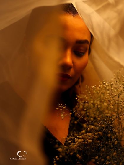 An artistic and abstract portrait, with the veil and flowers obscuring parts of her face. The image is more about mood and texture than a clear representation.