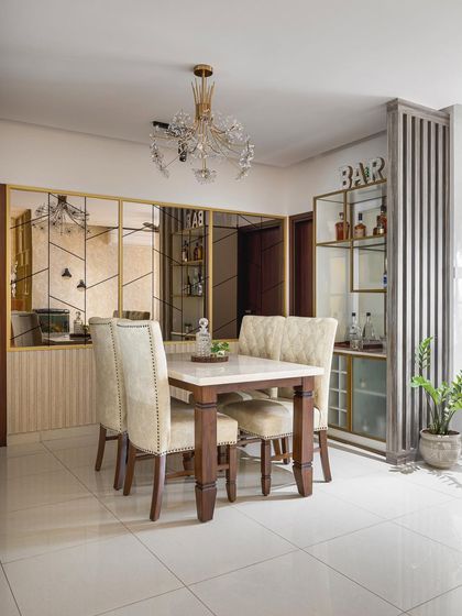 This dining room is full of reflective surfaces, from the crystal chandelier to the large mirror wall with gold-finish geometric detailing. According to Vastu, a mirror reflecting the dining table is believed to enhance health and wealth.