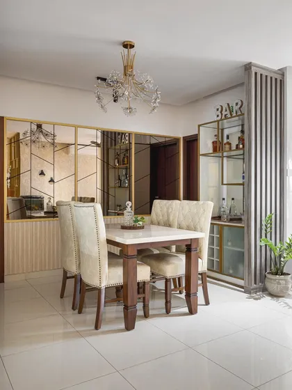 This dining room is full of reflective surfaces, from the crystal chandelier to the large mirror wall with gold-finish geometric detailing. According to Vastu, a mirror reflecting the dining table is believed to enhance health and wealth.