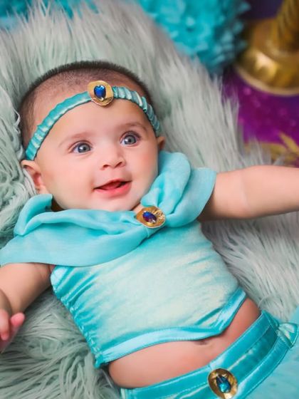 Your wish is our command. This newborn photoshoot features a custom-made Princess Jasmine outfit in her iconic turquoise blue, complete with a matching jeweled headband.