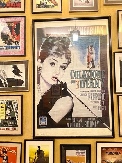 A wall of vintage movie posters at a cafe in Khan Market, Delhi, featuring classics like 'Breakfast at Tiffany's'.
