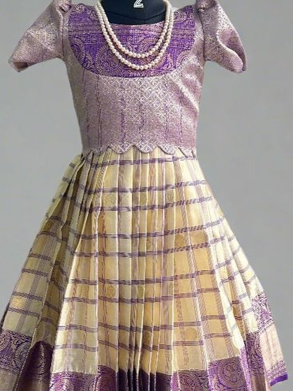 This kids' lehenga showcases a beautiful checkered pattern on the skirt with a rich purple brocade blouse and border. It's a timeless design made from a semi-Kanchi saree, perfect for your little one.
