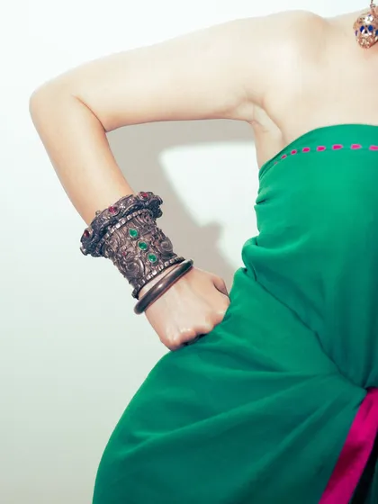 A detail shot of the heavy, antique-style cuff bracelet worn with the modern saree drape.