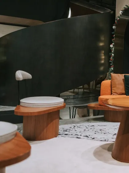 A stylish waiting area featuring custom curved wooden tables and comfortable seating. This design moves away from traditional lobby furniture to create a more relaxed and sophisticated lounge-like experience for visitors.