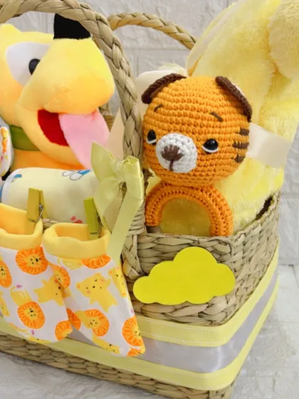 This image captures the adorable combination of the hand-knitted toy and soft booties, clipped to the side of the basket for a charming presentation.