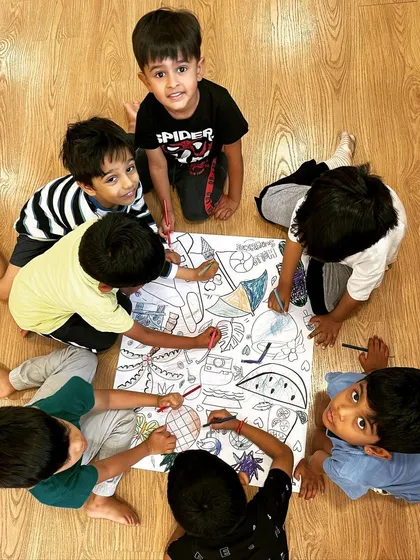 Collaboration in our creative corner. A group of boys works together on a giant coloring sheet, a simple activity that encourages sharing, communication, and collective artistic expression.