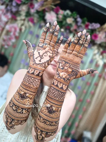 A full bridal design with the couple's initials "YK" elegantly placed in a cartouche on one hand, surrounded by traditional elephant and procession motifs.
