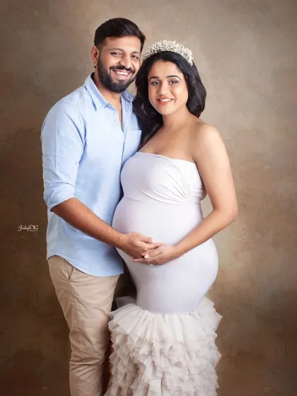A stunning portrait of an expecting couple. The mom to be looks radiant in a white gown and crown, perfect for a classic maternity look.