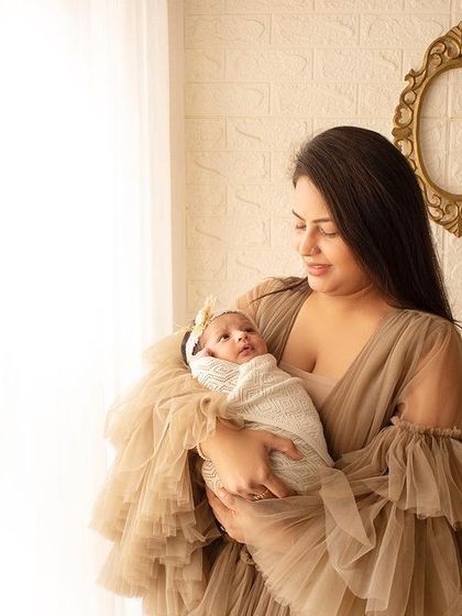 A new mother looking at her baby by the window. The soft, natural light creates a beautiful, gentle mood for this newborn portrait.