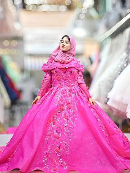 This vibrant fuchsia ball gown is a masterpiece of color and craftsmanship. The off-shoulder design and intricate floral embroidery make it a bold and unforgettable statement piece.
