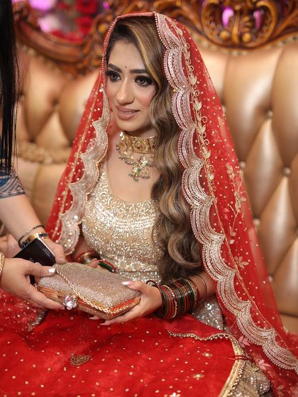 A candid shot of the bride during her engagement ceremony, holding a clutch and looking on as the event unfolds.