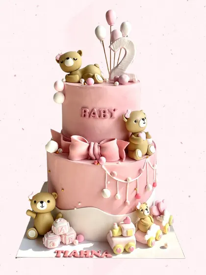Pretty in pink for Tiahna's 2nd birthday! This three-tiered cake is a teddy bear paradise, with cute bears, a big pink bow, and even a little toy train.