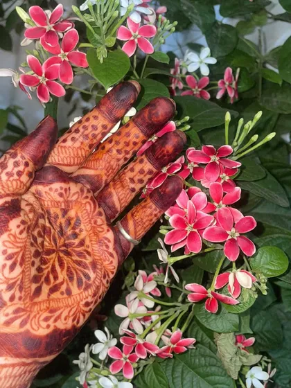 My henna-stained hand among the flowers. The deep brown of the mehndi complements the natural beauty of the flowers perfectly.