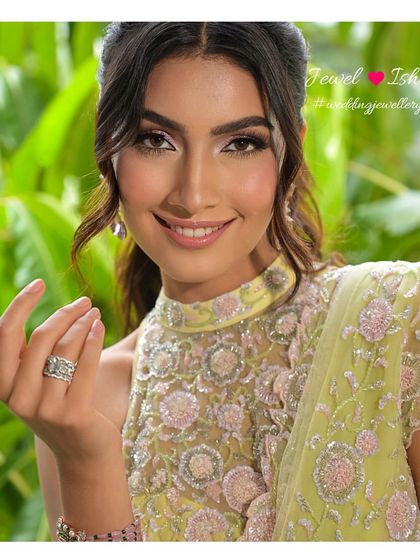 A smile that sparkles. The close-up shows the delicate design of the pink gemstone earrings and a statement diamond ring, perfect for a modern bride's engagement or reception look.