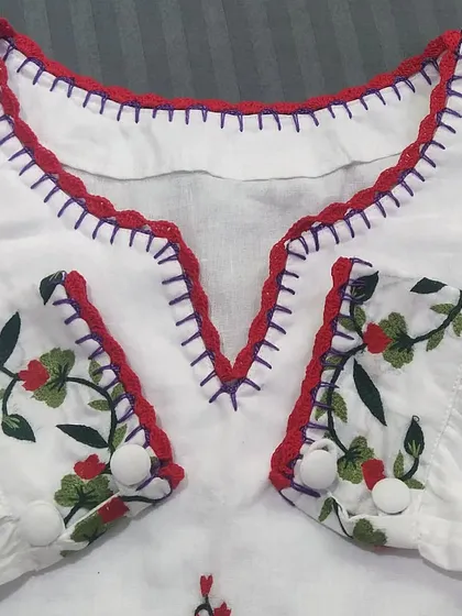 A closer look at the V-neckline, showing how the red crochet lace complements the purple embroidery stitches on the top.