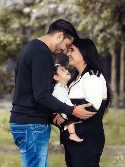 A tender family moment captured outdoors. The way their daughter looks up at them shows the deep connection and love within the family.