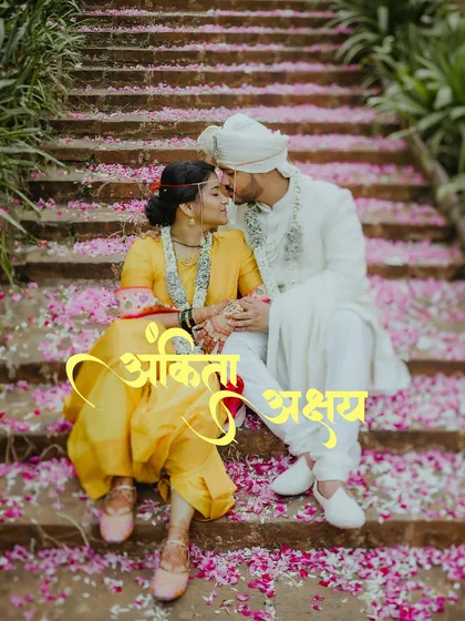 A classic romantic portrait from a Maharashtrian wedding, with the couple seated on steps showered in flower petals. This image highlights the beauty of traditional ceremonies.