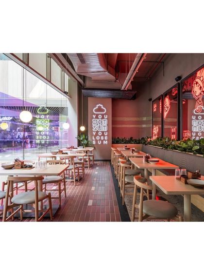 This view captures the full length of the restaurant, showing how we balanced quirky elements like neon signs with the warmth of brick tiles and versatile furniture to create a welcoming atmosphere for all guests.