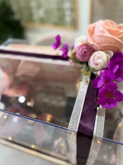 A beautiful floral accent made of artificial roses and orchids adorns the corner of the trousseau box, adding lasting beauty.