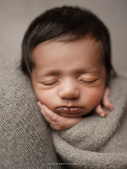 A detailed close-up of a newborn's face, with their tiny hand tucked under their chin. I love capturing these fleeting details, from the soft hair to the perfect little lips.