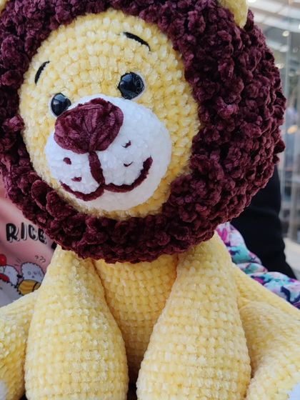 A close-up on the friendly, hand-stitched face of my custom lion plushie.